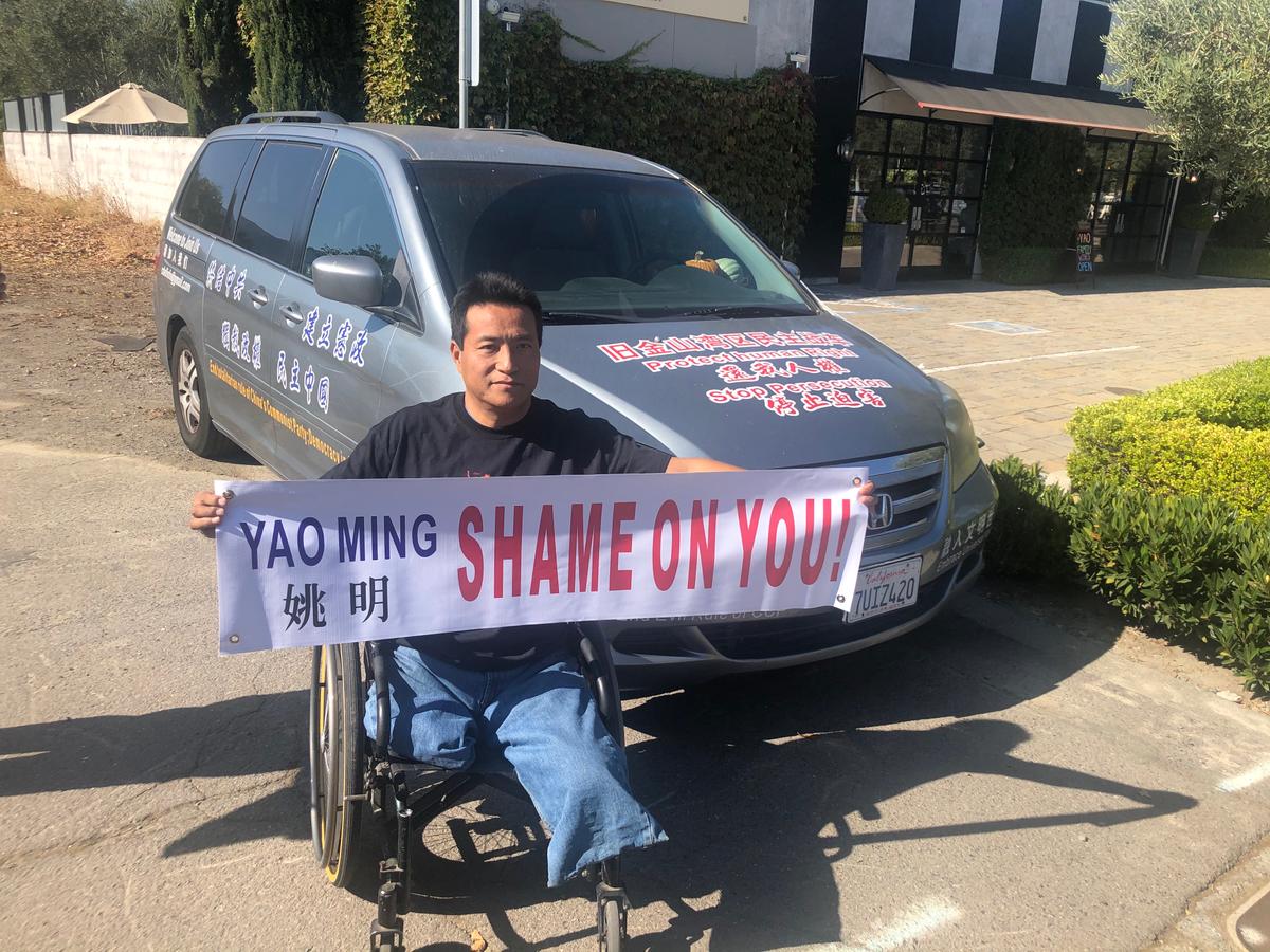 Protester Fang Zheng holds a banner in front of Yao Ming's restaurant. (Nathan Su/The Epoch Times)