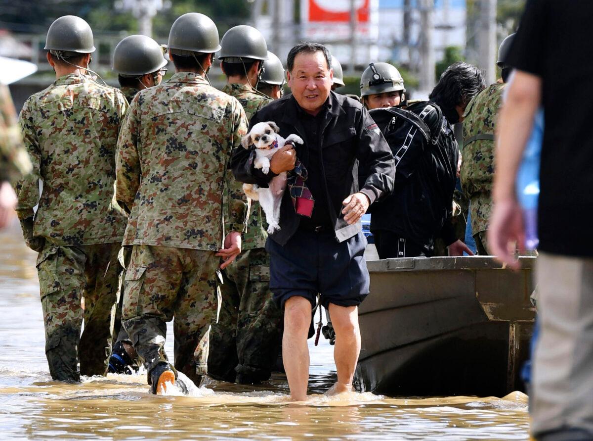 An evacuee with a dog is rescued by Self-Defense force members as the city is hit by Typhoon Hagibis, in Motomiya, Fukushima prefecture, northern Japan, on Oct. 13, 2019. (Kyodo News via AP)