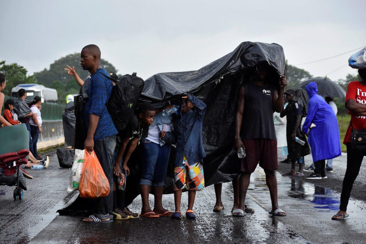 Migrants shelter from the rain as members of the National Guard (not pictured) conduct an operation to halt a caravan of migrants from Africa, the Caribbean and Central America, in Tuzantan, Mexico, on Oct. 12, 2019. (Jacob Garcia/Reuters)