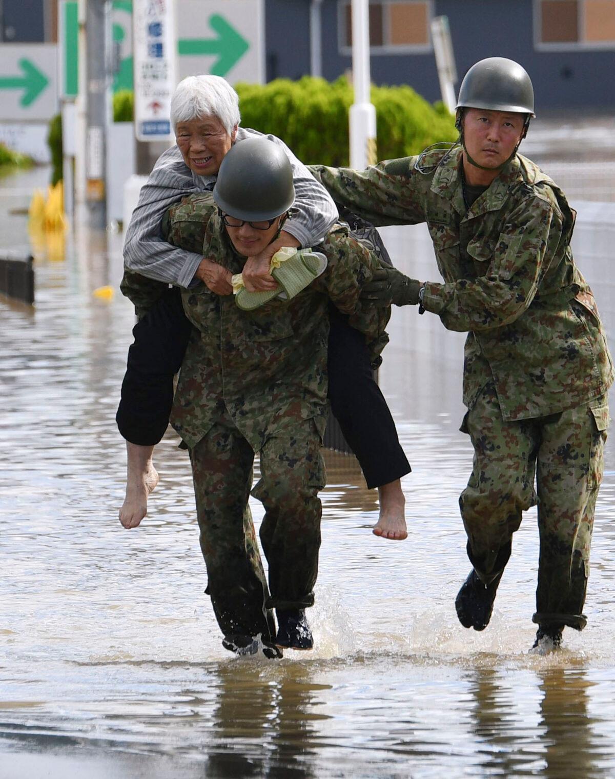 An evacuee is helped by Japan Self-Defense Forces' members as the city is hit by Typhoon Hagibis, in Motomiya, Fukushima prefecture, northern Japan, on Oct. 13, 2019. (Kyodo News via AP)