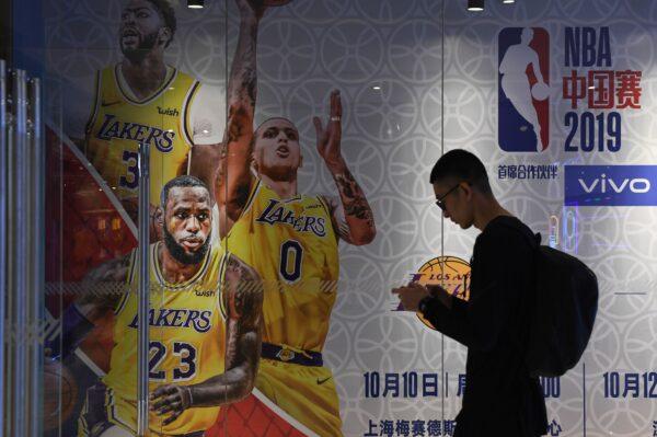 A man walks past an advertisement for scheduled exhibition games in China between the LA Lakers and Brooklyn Nets, at the National Basketball Association store in Beijing on Oct. 9, 2019. (Greg Baker/AFP via Getty Images)