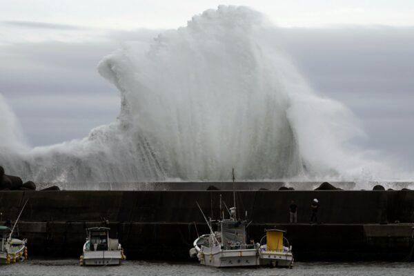 Men look at fishing boats as surging waves hit against the breakwater while Typhoon Hagibis approaches at a port in town of Kiho, Mie Prefecture, Japan on Oct. 11, 2019. (Toru Hanai/AP Photo)