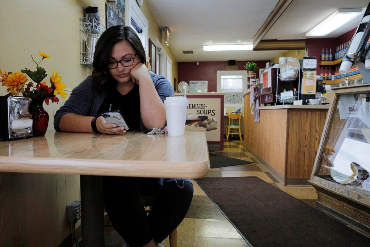 Carlee Giordano looks at her mobile phone at the Morning Emporium Coffee House in Precinct 7, where the vote was split 876/876 between Donald Trump and Hillary Clinton in 2016, in Saginaw Township, Michigan on Oct. 11, 2019. REUTERS/Brian Snyder