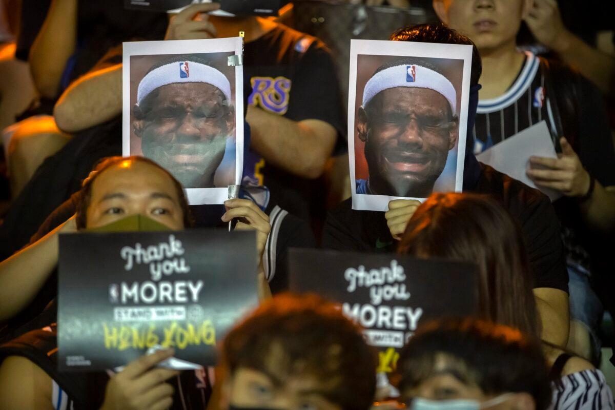 Demonstrators hold up photos of LeBron James grimacing, back, and signs expressing thanks to Houston Rockets General Manager Daryl Morey, front, during a rally at the Southorn Playground in Hong Kong on Oct. 15, 2019. (Mark Schiefelbein/AP Photo)