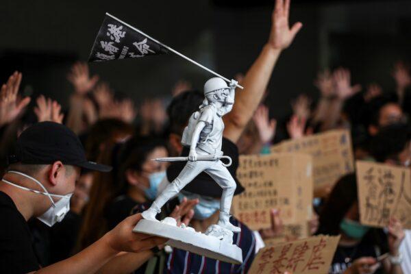 A figurine of a Hong Kong anti-government protester is held up as people gather at West Kowloon Law Courts Building to show their support to 96 anti-government protesters who were arrested days ago in Hong Kong, Oct. 2, 2019. (Athit Perawongmetha/Reuters)
