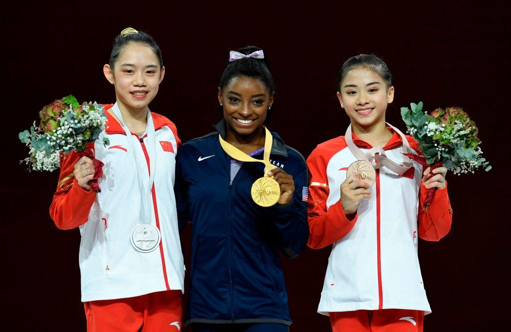 (L-R) Second-placed China's Liu Tingting, first-placed USA's Simone Biles, and third-placed China's Li Shijia celebrate on the podium with their medals for beam (©Getty Images | <a href="https://www.gettyimages.com.au/detail/news-photo/second-placed-chinas-liu-tingting-first-placed-usas-simone-news-photo/1175578969">THOMAS KIENZLE/AFP</a>)