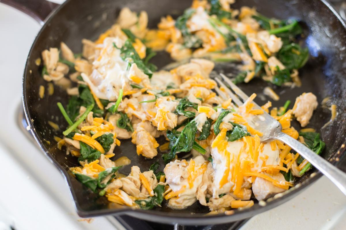 Two full cups of spinach get wilted in the skillet with the chicken, then rolled right into the tortillas. (Caroline Chambers)
