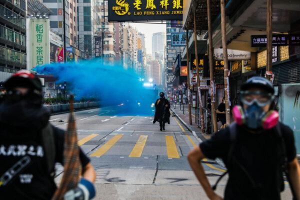 Protesters run from advancing police as they deploy a water cannon on a road in the Tsim Sha Tsui district in Hong Kong on Oct. 20, 2019. (Dale De La Rey/AFP via Getty Images)
