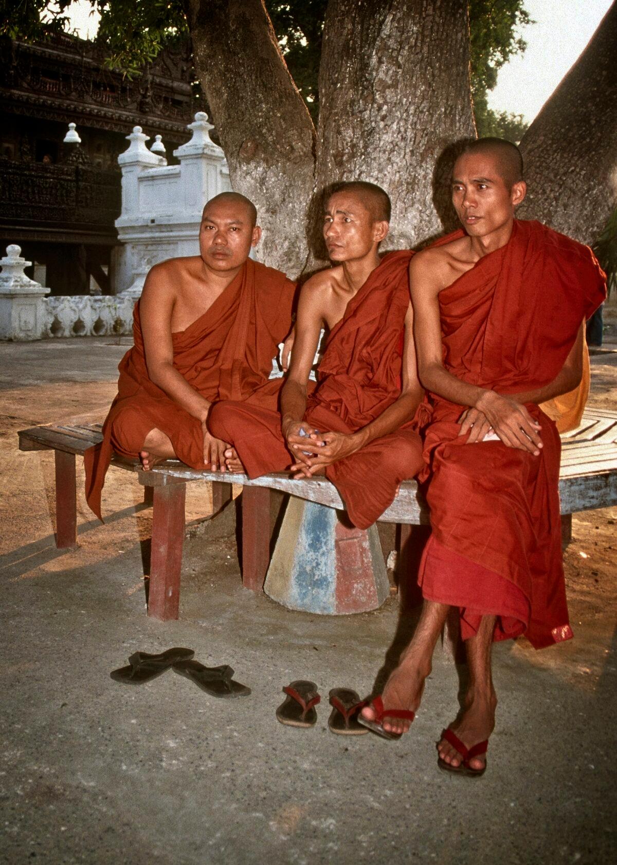 Three Buddhist monks take a break together under a shade tree on the grounds of a pagoda. (Fred J. Eckert)