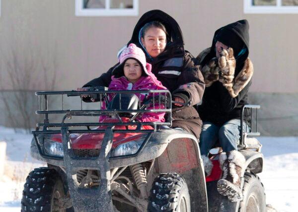 A woman takes children to school on a fourwheel vehicle at Attawapiskat First Nation, Ont., in a file photo. (The Canadian Press/Adrian Wyld)