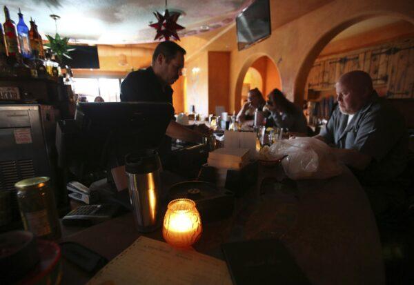 Maria's restaurant staff work in candle light as they choose to stay open with a limited menu offering after losing power in downtown Grass Valley, Calif., on the evening of Oct. 23, 2019. (Elias Funez/The Union via AP)
