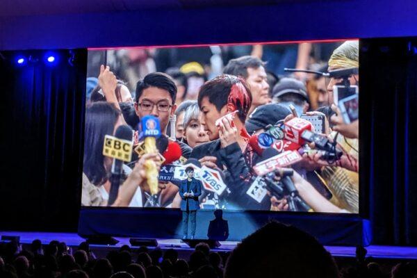 Denise Ho at the Oslo Freedom Forum in New York, N.Y., on Oct. 23, 2019. The screen in the background shows Ho attacked with red paint.(Edwin Huang/The Epoch Times)