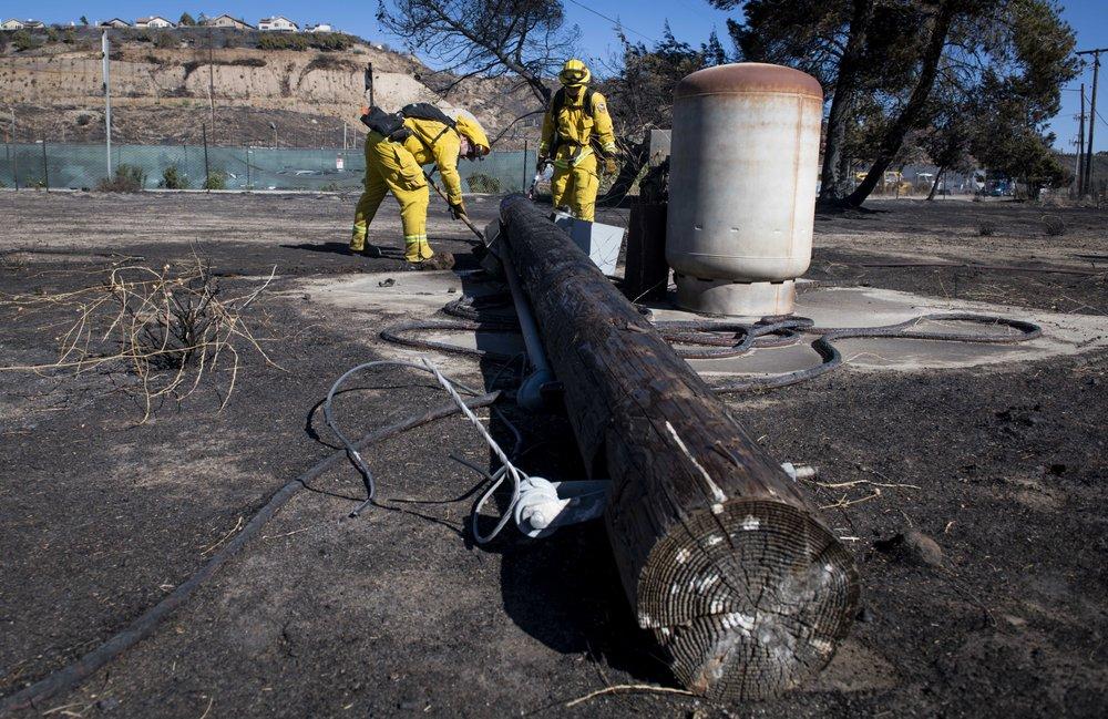 Firefighters with Cal Fire examine a burned down low voltage power pole during the Tick Fire in Santa Clarita, Calif. on Oct. 25, 2019. (Christian Monterrosa/AP Photo)