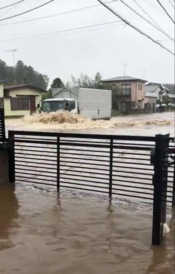 A truck drives along a flooded street in Yachimata city, in Chiba prefecture, after flooding and mudslides brought about by torrential rains in eastern Japan on Oct. 25, 2019, in this still image taken from social media video. (Hiroya Hirayama/via Reuters)