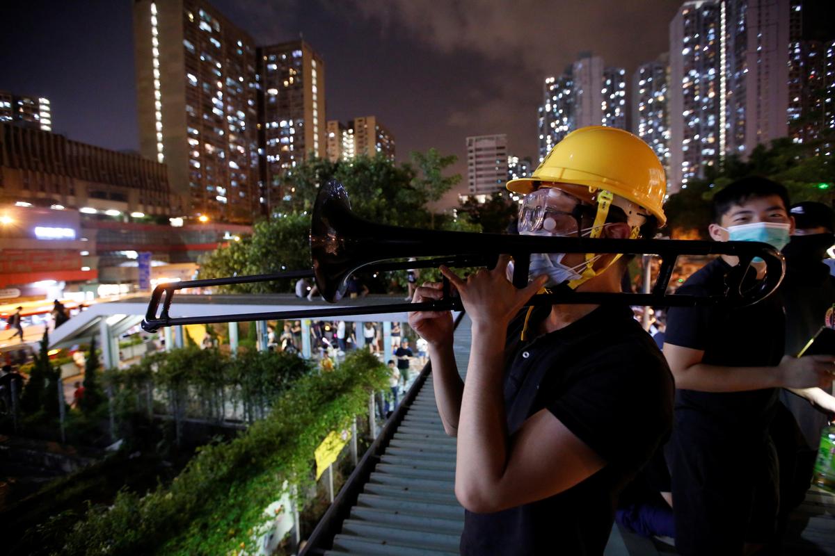A masked trombonist plays the first notes of “Glory to Hong Kong” above the crowds in Wong Tai Sin Square on the night of the mid-autumn festival in Hong Kong on Sept. 13, 2019. (James Pomfret/Reuters)