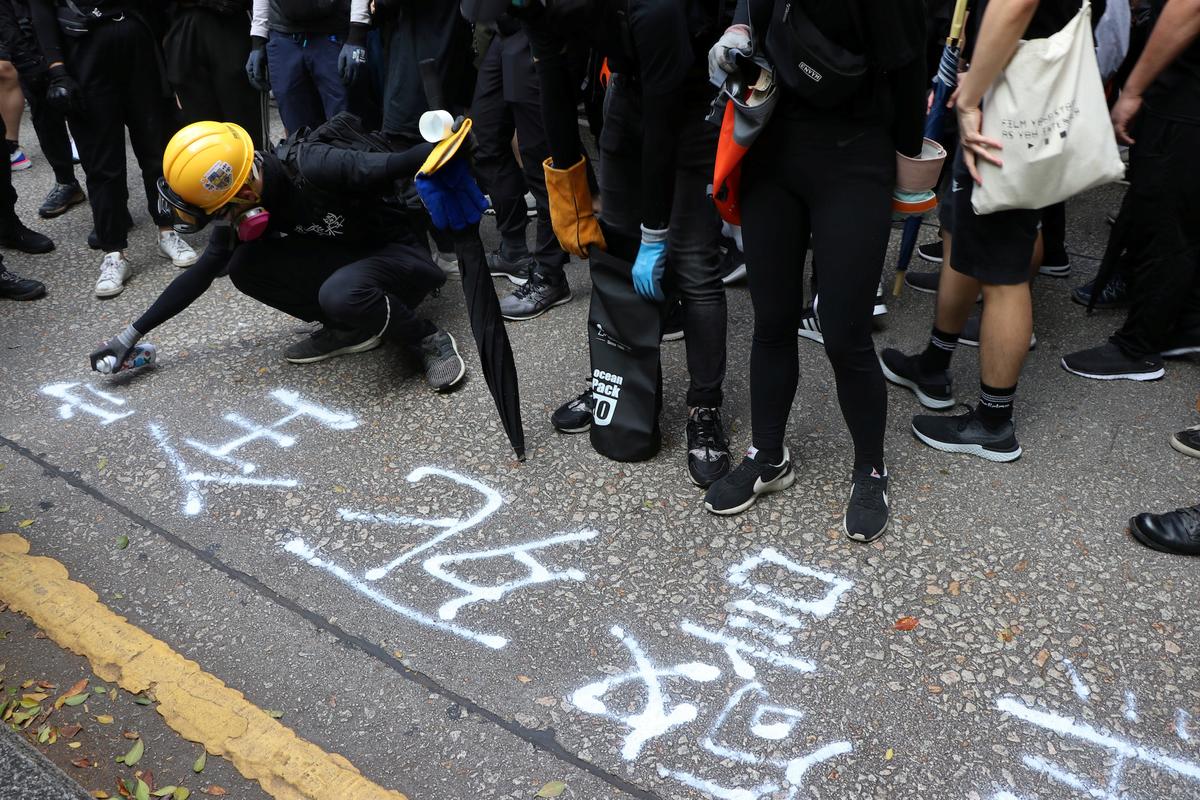 Yan, the son of a police officer, spray-paints a protest slogan on the ground at a protest in Hong Kong on Oct. 20, 2019. (Jessie Pang/Reuters)