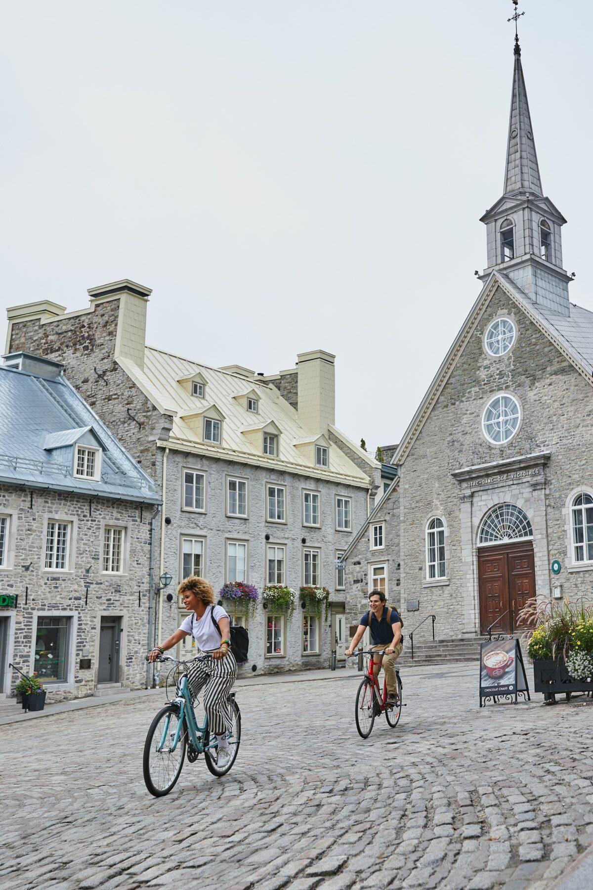 A couple of cyclists pass by Notre-Dame-des-Victoires Church. (Courtesy of Martin Laporte/Quebec Original)