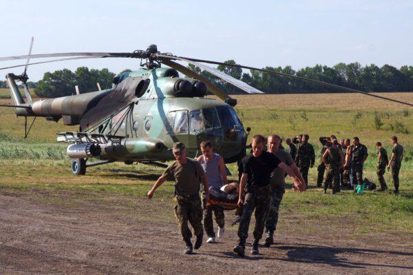 An MI-8 helicopter is seen in the background, with engines of joint Ivchenko-Progress and Motor Sich production, as Ukrainian soldiers carry their wounded comrade on a stretcher, in a field near Zaporizhzhya, Ukraine, on July 31, 2014. (Alexey Kravtsov/AFP/Getty Images)