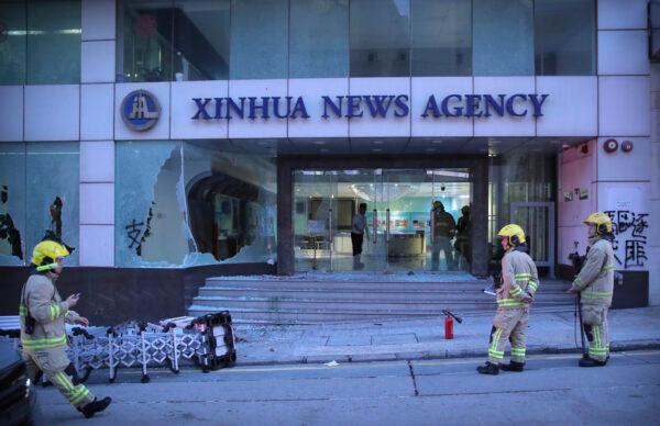 Firefighters stand outside the offices of China's Xinhua News Agency after its windows were shattered during protests in Hong Kong, on Nov. 2, 2019. (AP Photo/Kin Cheung)