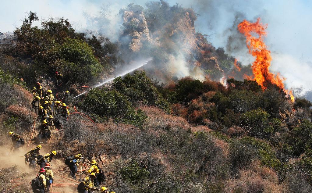 Firefighters at work during a wildfire threatening nearby hillside homes in the Pacific Palisades neighborhood in Los Angeles on Oct. 21, 2019 (©Getty Images | <a href="https://www.gettyimages.com.au/detail/news-photo/firefighters-work-during-a-wildfire-threatening-nearby-news-photo/1182541196">Mario Tama</a>)