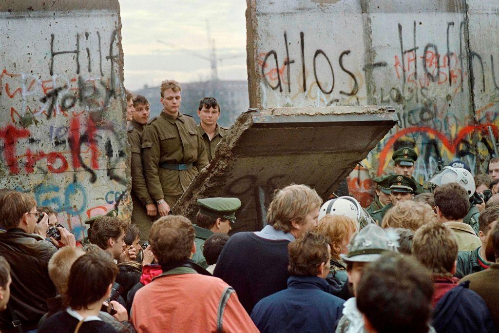 West Berliners crowd in front of the Berlin Wall early Nov. 11, 1989, as they watch East German border guards demolishing a section of the wall in order to open a new crossing point between East and West Berlin, near the Potsdamer Square. Two days before, Gunter Schabowski, the East Berlin Communist Party boss, declared that starting from midnight, East Germans would be free to leave the country without permission at any point along the border, including the crossing-points through the Wall in Berlin. (GERARD MALIE/AFP via Getty Images)