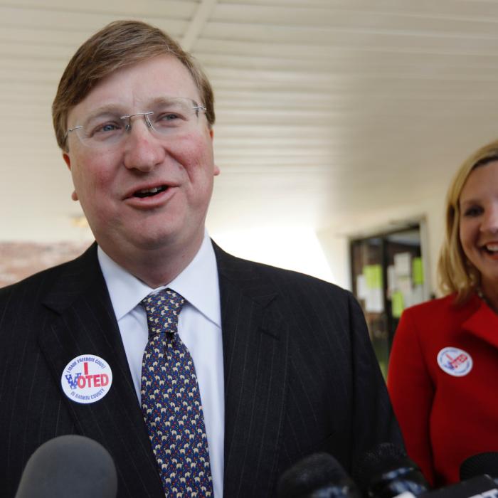 Lt. Gov. Tate Reeves, left, speaks with reporters while his wife, Elee Reeves, laughs at his response outside their Flowood, Miss., voting precinct, on Nov. 5, 2019. (AP Photo/Rogelio V. Solis)