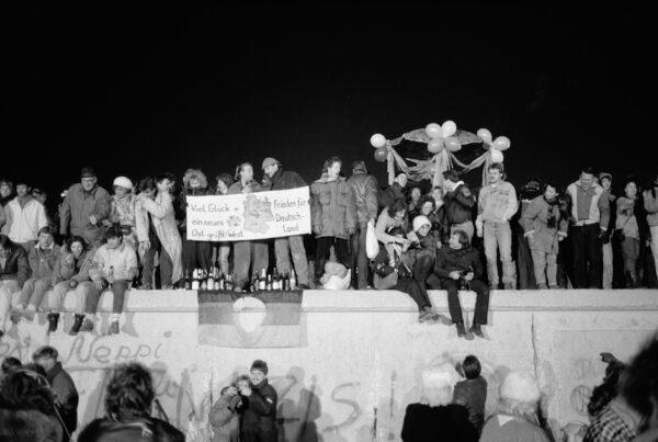 A view from the east shows Berliners gathered on the Berlin Wall to celebrate the New Year and the effective end of the city's partition on Dec. 31, 1989. A banner reads "Good luck and peace for a new Germany - East Greets West." (Steve Eason/Hulton Archive/Getty Images)