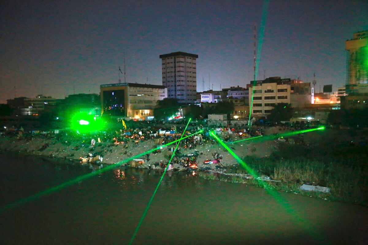 Anti-government protesters shoot laser lights at security forces during clashes on a bridge leading to the Green Zone government areas during ongoing protests in Baghdad, Iraq, on Nov. 6, 2019. (Khalid Mohammed/AP Photo)