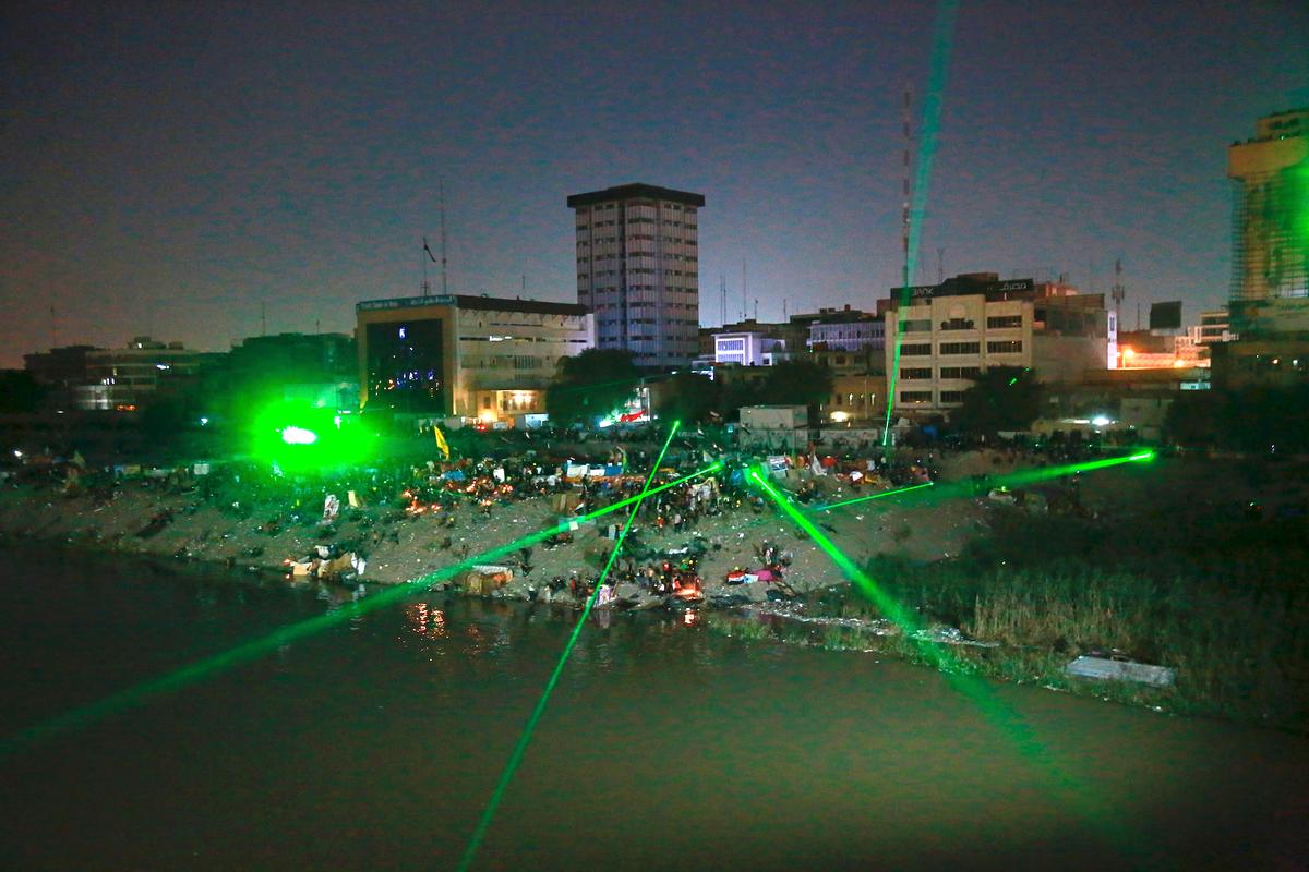 Anti-government protesters shoot laser lights at security forces during clashes on a bridge leading to the Green Zone government areas during ongoing protests in Baghdad, Iraq, on Nov. 6, 2019. (AP Photo/Khalid Mohammed)