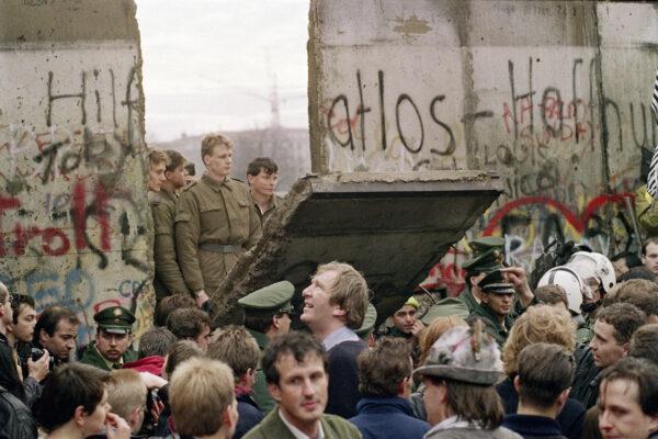 West Berliners crowd in front of the Berlin Wall early Nov. 11, 1989, as they watch East German border guards demolishing a section of the wall. (Gerard Malie/AFP via Getty Images)