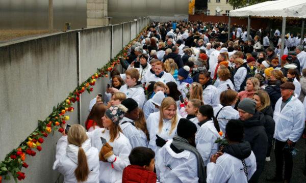 People place roses into a gap at the Wall memorial during a ceremony marking the 30th anniversary of the fall of the Berlin Wall at Bernauer Strasse in Berlin, Germany on Nov. 9, 2019. (Fabrizio Bensch/Reuters)