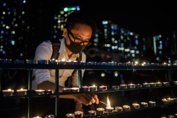 A man lights candles on a street handrail as he pays respects outside the carpark where 22-year-old student Alex Chow fell during a recent protest in the Tseung Kwan O district on the Kowloon side of Hong Kong early on Nov. 9, 2019. (Anthony Wallace/AFP via Getty Images)