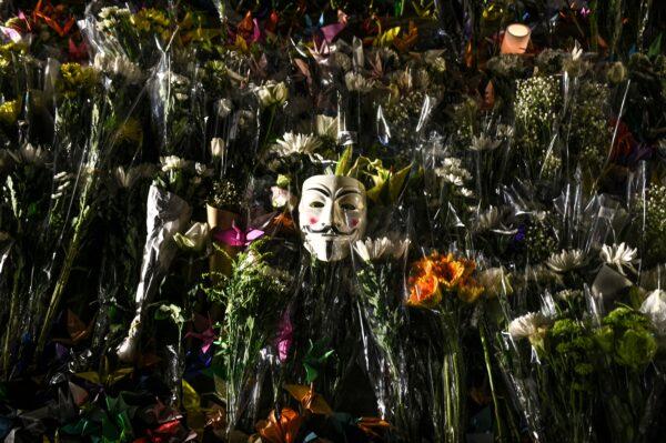 A Guy Fawkes mask is left among flowers during a prayer rally in Tamar Park in Hong Kong on Nov. 9, 2019, in memory of deceased university student Alex Chow. (Philip Fong/AFP via Getty Images)