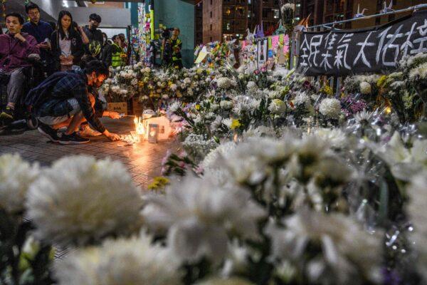 Mourners pay their respects next to flowers and a banner which reads "From all of us - God bless Chow Tsz-Lok" at the site where student Alex Chow, 22, fell during a recent protest on the Kowloon side of Hong Kong on Nov. 8, 2019. (Anthony Wallace/AFP via Getty Images)