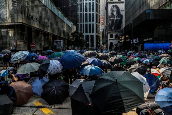 Demonstrators shield beneath umbrellas as police arrive during a flash mob protest in the Central district in Hong Kong on November 13, 2019. (Dale De La Rey/AFP via Getty Images)