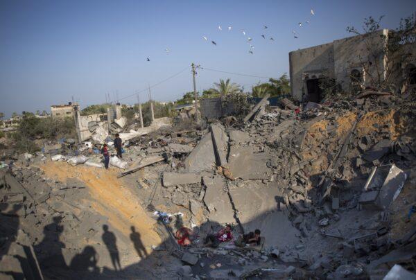 Palestinians sit amid the rubble of their destroyed house following overnight Israeli missile strikes, in the town of Khan Younis, southern Gaza Strip, on Nov. 14, 2019. (Khalil Hamra/AP Photo)