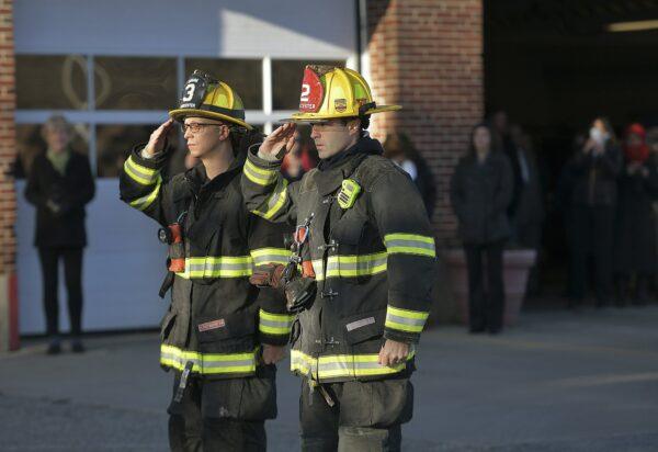 Two firefighters salute at Grove Street Fire Station after putting the flag at half staff after Lt. Jason Menard died in an overnight fire in Worcester, Mass., on Nov. 13, 2019. (Christine Peterson/Worcester Telegram & Gazette via AP)