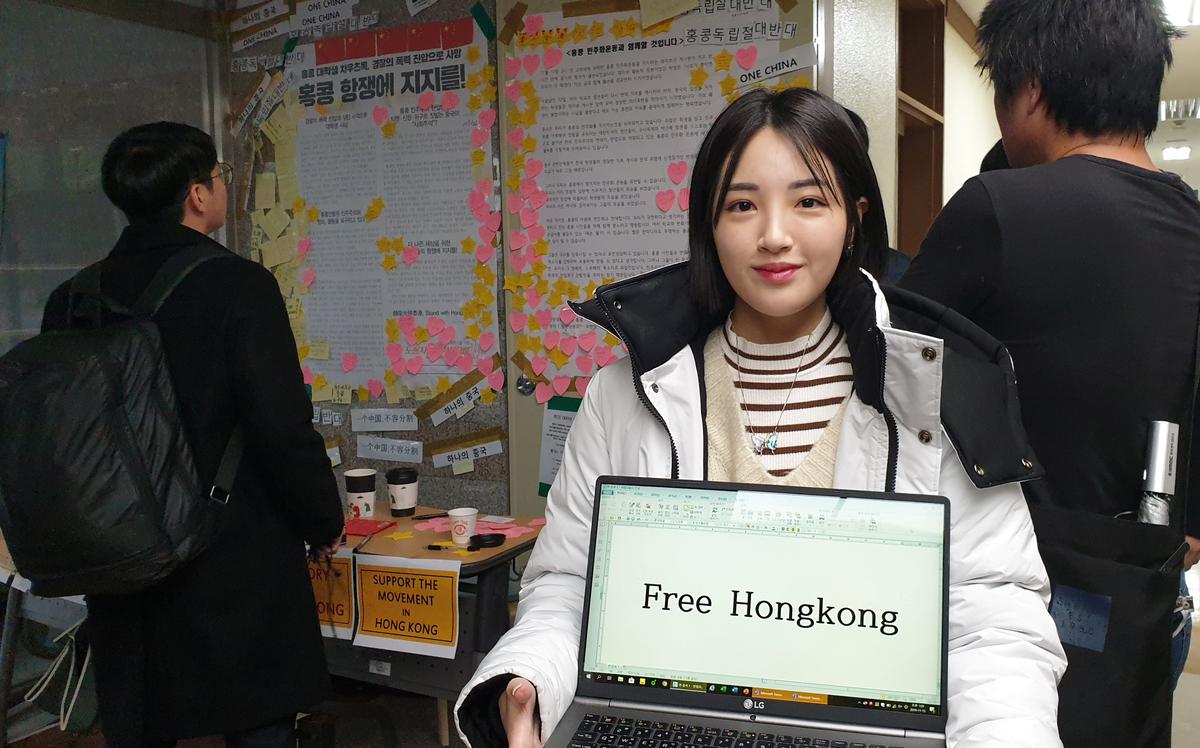 A university student Kang Min-seo poses for photographs in front of a poster supporting Hong Kong protesters at a university in Seoul, South Korea on Nov. 15, 2019. (Choi Ha-young/Reuters)