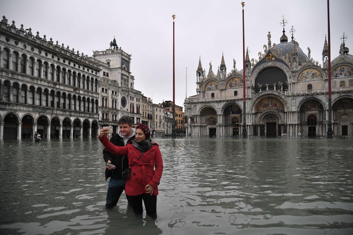People take selfie photos at the flooded St. Mark's square by St. Mark's Basilica in Venice on early on Nov. 13, 2019. (Marco Bertorello/AFP via Getty Images)