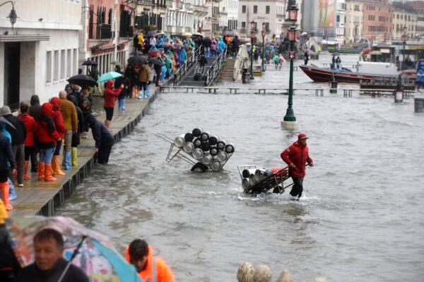 People walk on catwalks set up on the occasion of a high tide, in a flooded Venice, Italy, on Nov. 12, 2019. (AP Photo/Luca Bruno)