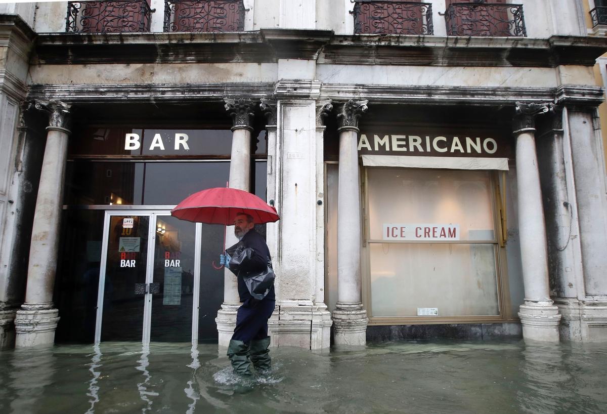 A man walks past a closed cafe in a flooded Venice, Italy, on Nov. 12, 2019. (AP Photo/Luca Bruno)