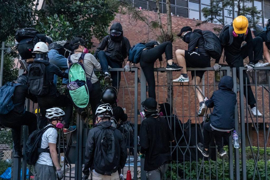 Protesters climb over fences during an attempt to leave the Hong Kong Polytechnic University in Hong Kong on Nov.18, 2019. (Anthony Kwan/Getty Images)