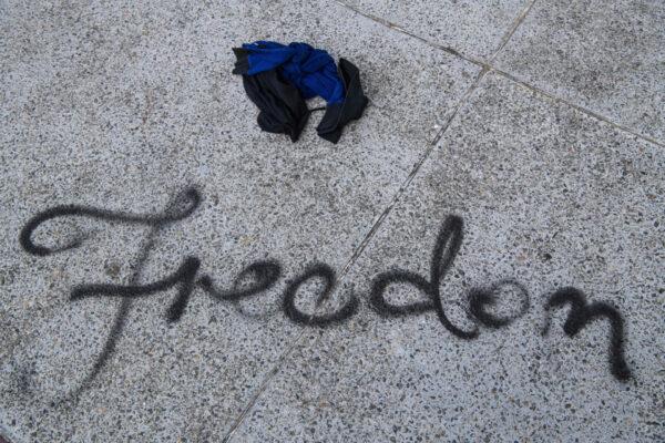 Discarded clothes are left on the ground near grafitti that reads "Freedom" in the campus of the Hong Kong Polytechnic University in the Hung Hom district of Hong Kong on Nov. 18, 2019. (Anthony Wallace/AFP via Getty Images)