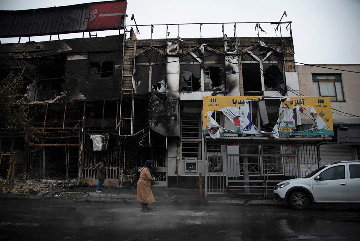 People walk past buildings that burned during protests following the authorities' decision to raise gasoline prices, in the city of Karaj, west of the capital Tehran, Iran on Nov. 18, 2019. (Masoume Aliakbar/ISNA via AP)