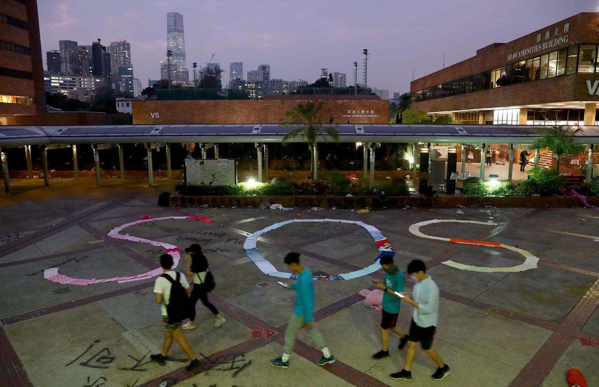 People pass by an "SOS" sign written with clothes on the campus of the Hong Kong Polytechnic University (PolyU), in Hong Kong on Nov. 19, 2019. (Athit Perawongmetha/Reuters)