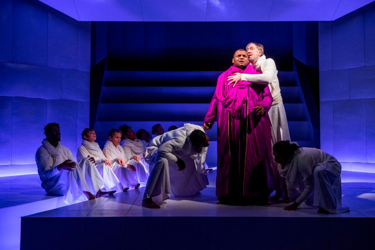 Oedipus (Kelvin Roston Jr.) and Teiresias (Christopher Donahue), the prophet who forewarns that the king will soon face horrible regret, surrounded by the cast. (Michael Brosilow)