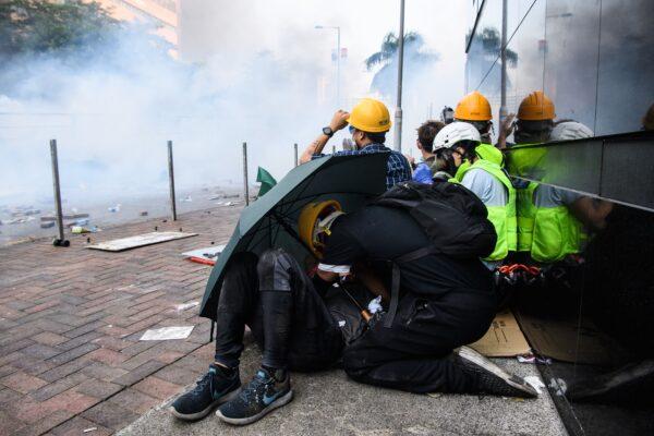 Tear gas is fired by police as protesters huddle during an attempt to escape the campus of the Hong Kong Polytechnic University in the Hung Hom district of Hong Kong on Nov. 18, 2019. (Anthony Wallace/AFP via Getty Images)