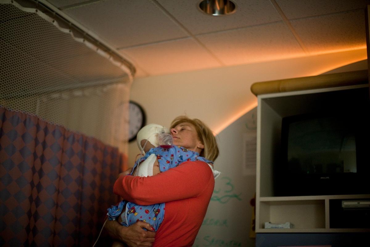 Barbara holding 6-year-old Teeba for comfort after surgery. (Photo courtesy of Ron Haviv)