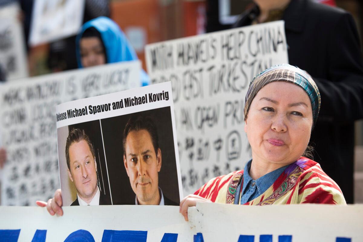 Turnisa Matsedik-Qira, of the Vancouver Uyghur Association, demonstrates against China's treatment of Uyghurs while holding a photo of detained Canadians Michael Spavor (L) and Michael Kovrig outside a court appearance for Huawei executive Meng Wanzhou at the B.C. Supreme Court in Vancouver on May 8, 2019. (Jason Redmond/AFP via Getty Images)