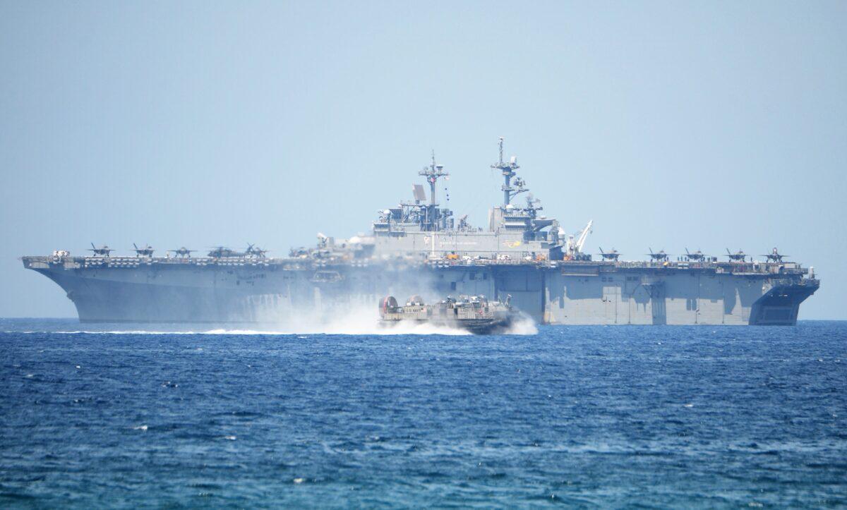 A U.S. Navy hovercraft speeds past the USS Wasp, a U.S. Navy multipurpose amphibious assault ship, during the amphibious landing exercises as part of the annual joint US–Philippines military exercise on the shores of San Antonio town, facing the South China Sea. (Ted Aljibe/AFP via Getty Images)